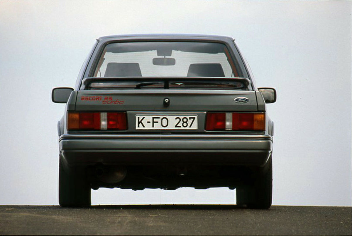 This archival image documents the 1986 Ford Escort Mark IV Turbo LHD rear view with scenic blue sky and is preserved in the Ford Heritage Vault as part of Ford Motor Company's historic photographic archive. Free for personal, non-commercial use. F...