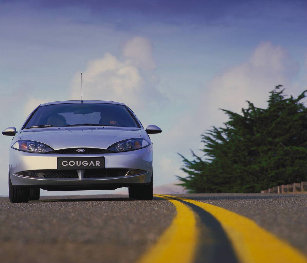 This archival image documents the 1998 Ford Cougar low front view on scenic road AR-2002-213709 and is preserved in the Ford Heritage Vault as part of Ford Motor Company's historic photographic archive. Free for personal, non-commercial use. Ford ...