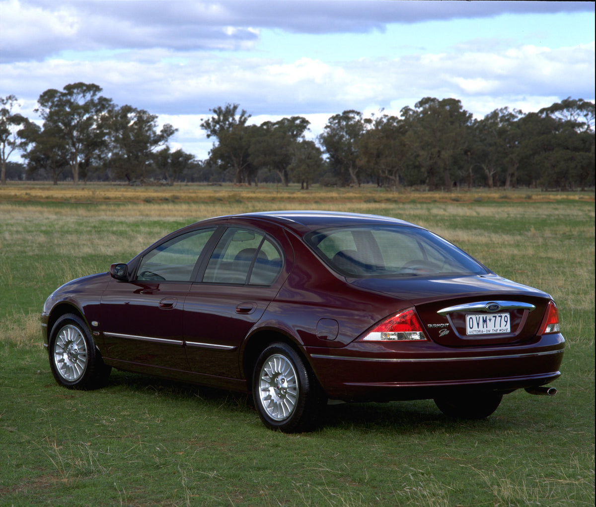 This archival image documents the 1998 Ford Falcon Fairmont Ghia rear view in scenic field with trees and is preserved in the Ford Heritage Vault as part of Ford Motor Company's historic photographic archive. Free for personal, non-commercial use....