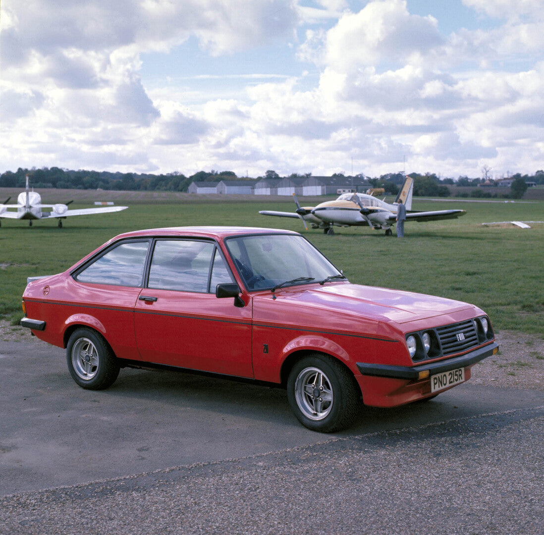 This archival image documents the 1976 Ford Escort Mark II RS 2000 on tarmac with planes 1976-910-RS and is preserved in the Ford Heritage Vault as part of Ford Motor Company's historic photographic archive. Free for personal, non-commercial use. ...