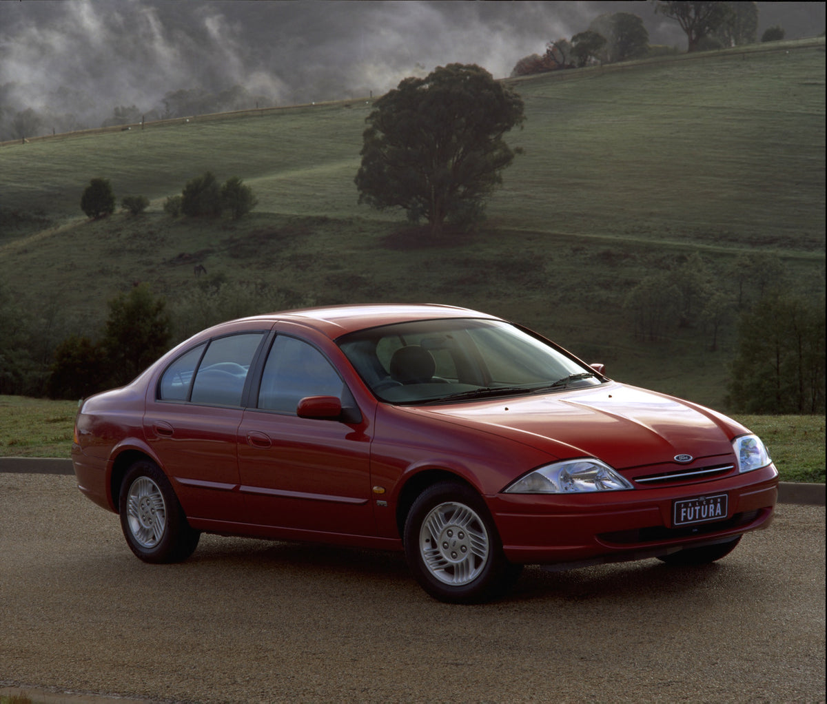 This archival image documents the 1998 Ford Falcon Futura on scenic road with trees and is preserved in the Ford Heritage Vault as part of Ford Motor Company's historic photographic archive. Free for personal, non-commercial use. Ford Heritage Vau...