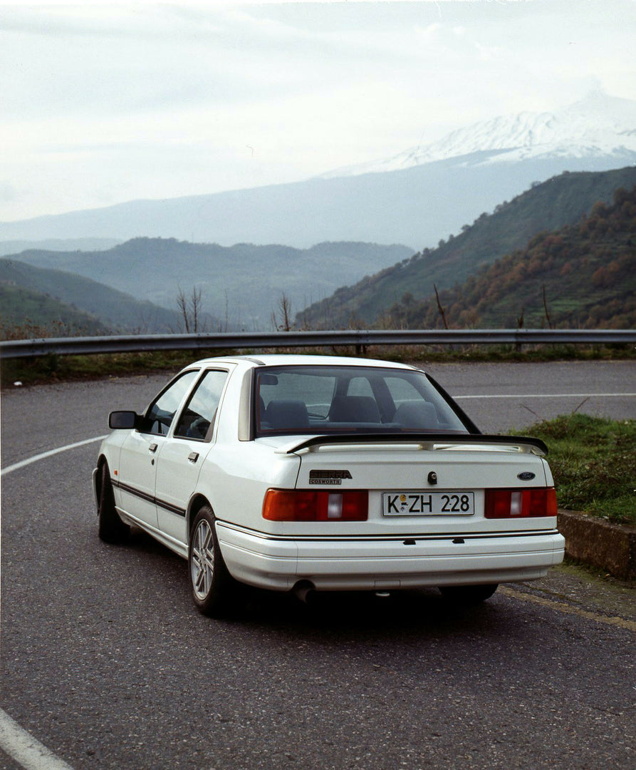 This archival image documents the 1987 Ford Sierra Cosworth LHD rear view on scenic mountain road and is preserved in the Ford Heritage Vault as part of Ford Motor Company's historic photographic archive. Free for personal, non-commercial use. For...