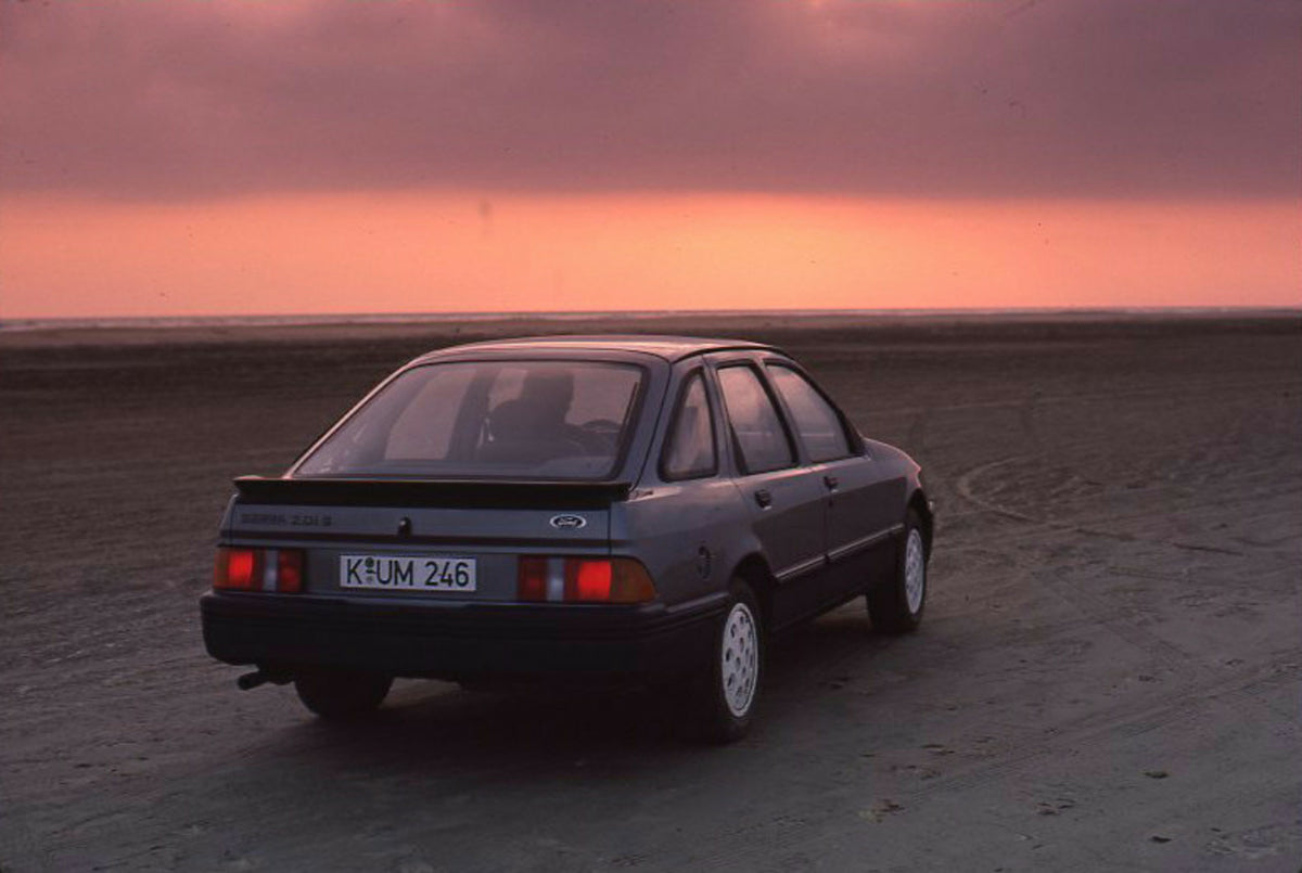 This archival image documents the 1985 Ford Sierra 2.0 IS LHD rear view on scenic beach with sunset and is preserved in the Ford Heritage Vault as part of Ford Motor Company's historic photographic archive. Free for personal, non-commercial use. F...