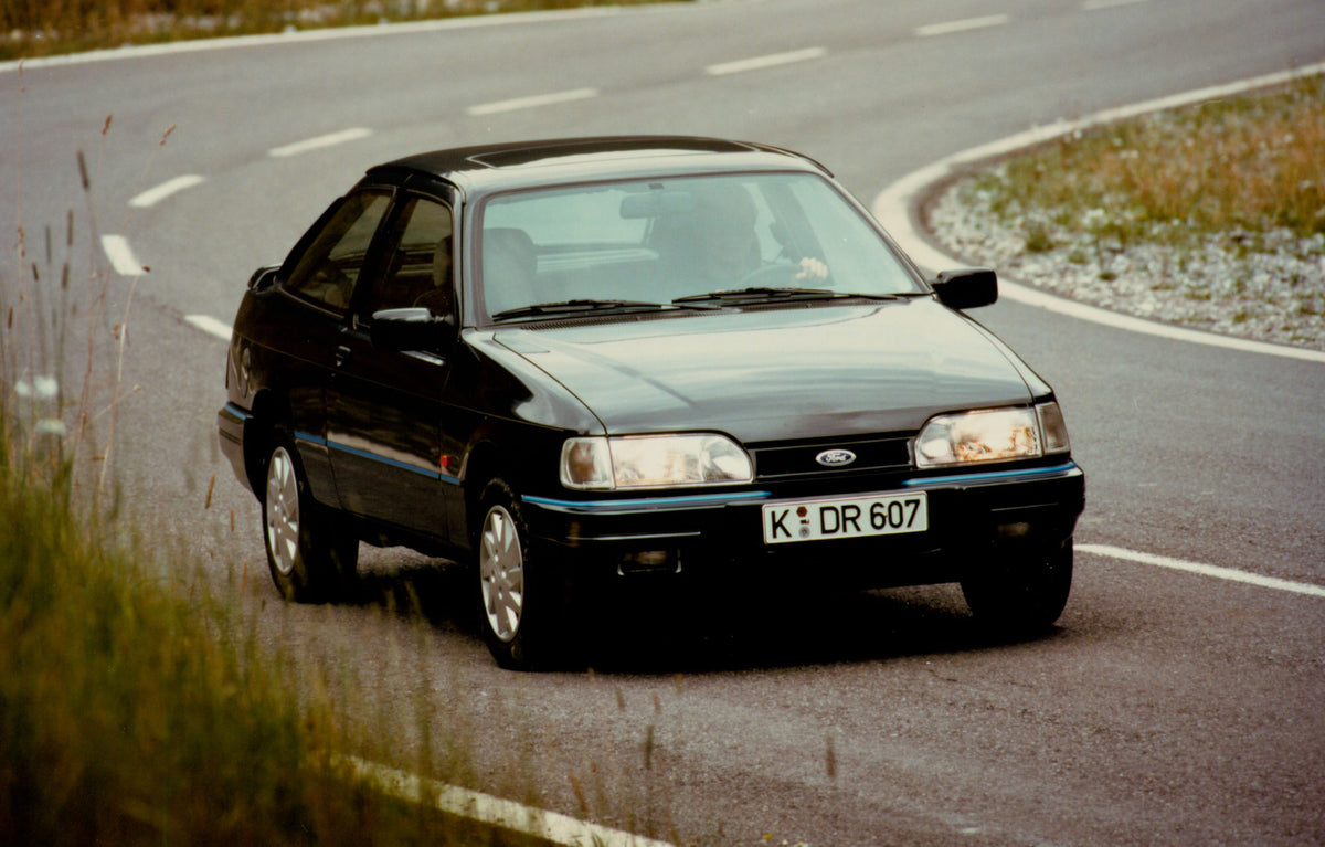 This archival image documents the 1990 Ford Sierra XR4i closeup on scenic road (AR-2007-5) and is preserved in the Ford Heritage Vault as part of Ford Motor Company's historic photographic archive. Free for personal, non-commercial use. Ford Herit...