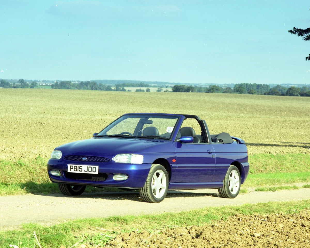 This archival image documents the 1996 Ford Escort Mark VI Cabriolet Ghia on scenic road and is preserved in the Ford Heritage Vault as part of Ford Motor Company's historic photographic archive. Free for personal, non-commercial use. Ford Heritag...