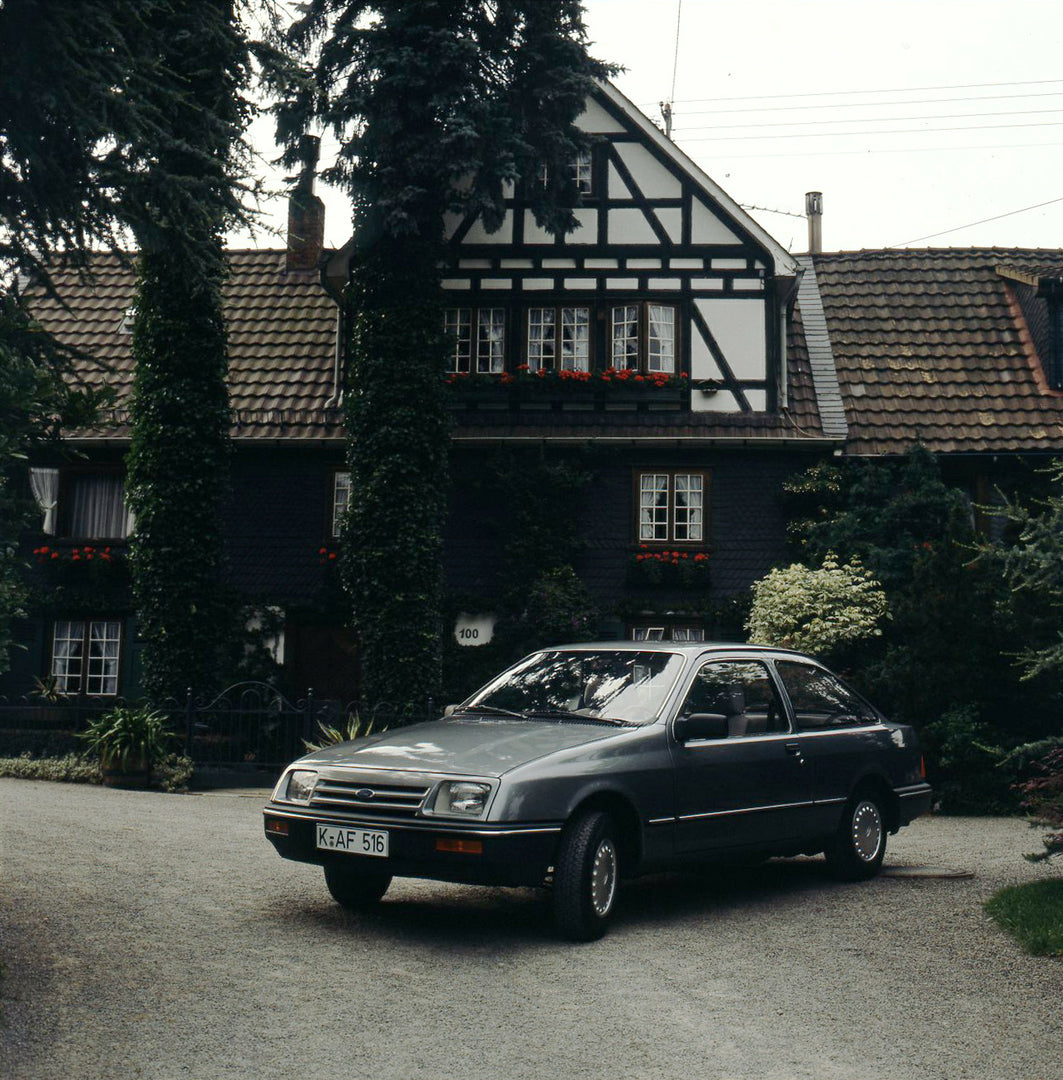 This archival image documents the 1983 Ford Sierra Mark I L in front of scenic house with shrubbery and is preserved in the Ford Heritage Vault as part of Ford Motor Company's historic photographic archive. Free for personal, non-commercial use. F...