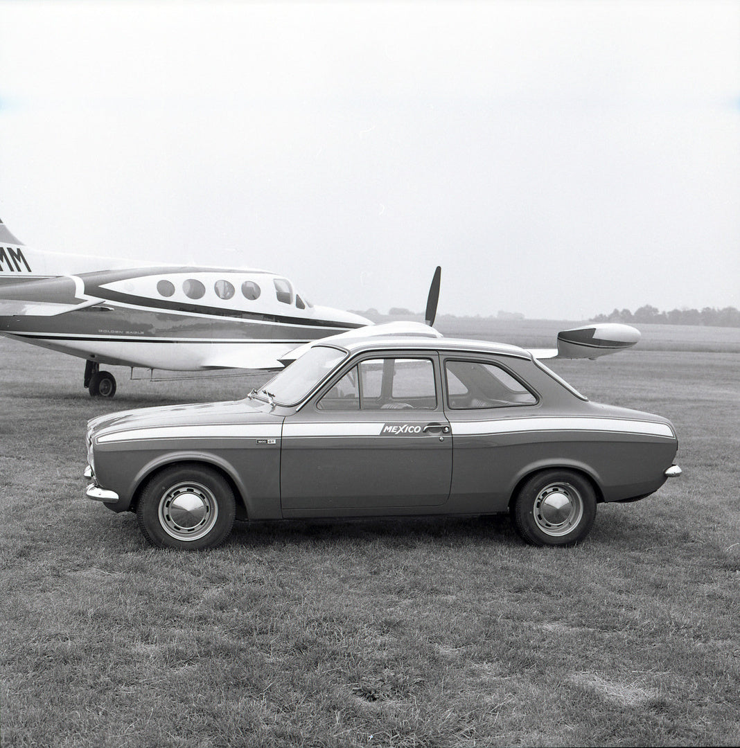 This archival image documents the 1971 Ford Escort Mexico MKI LHD side view in scenic field with plane and is preserved in the Ford Heritage Vault as part of Ford Motor Company's historic photographic archive. Free for personal, non-commercial use...