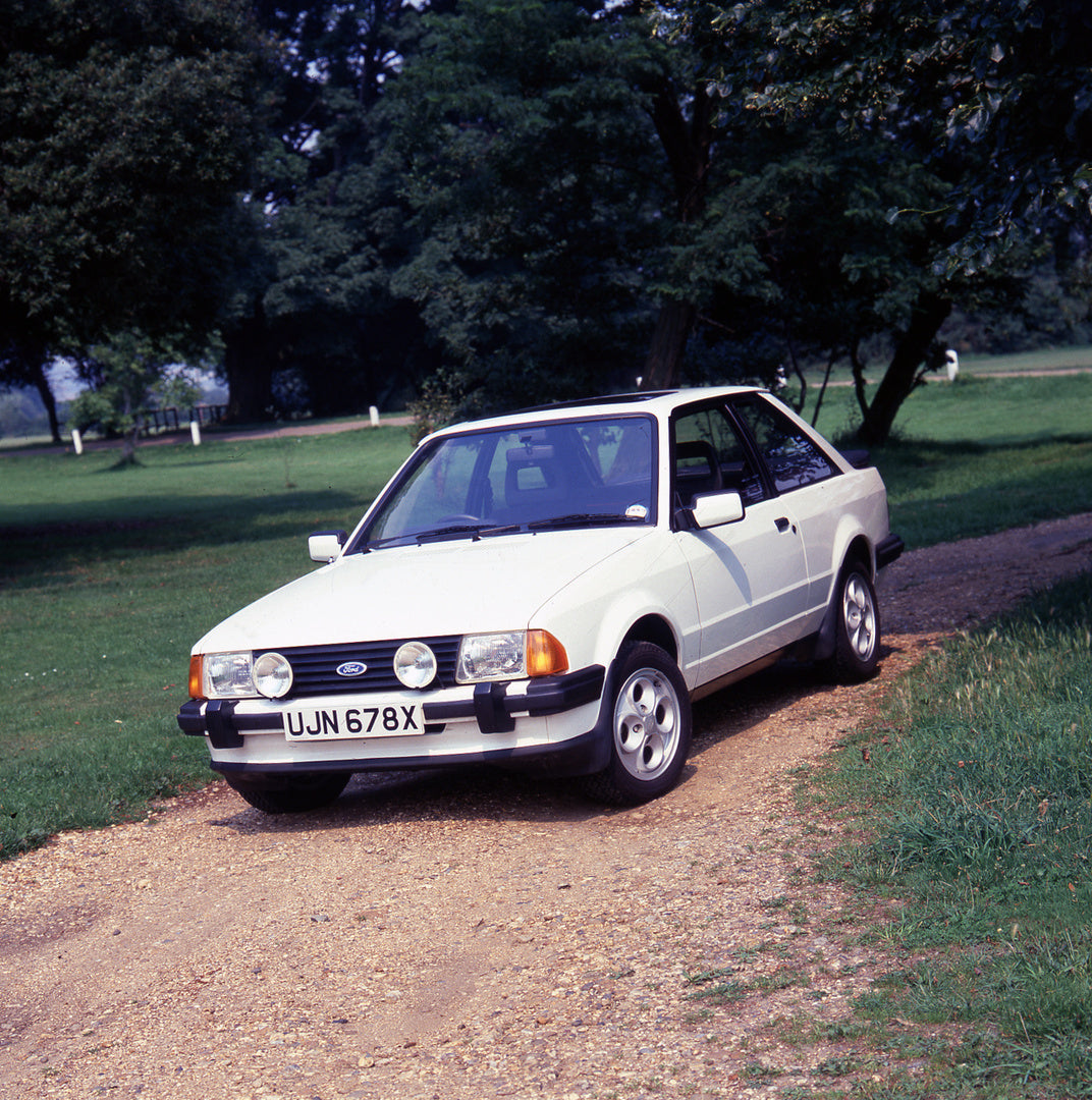 This archival image documents the 1981 Ford Escort Mark III XR3 on scenic road with trees and is preserved in the Ford Heritage Vault as part of Ford Motor Company's historic photographic archive. Free for personal, non-commercial use. Ford Herita...