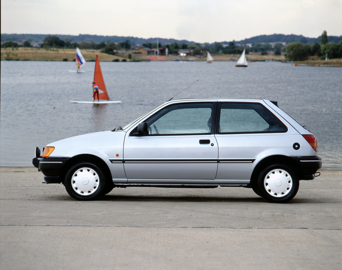 This archival image documents the 1990 Ford Fiesta Mark III S side view on beach with windsurfers in background and is preserved in the Ford Heritage Vault as part of Ford Motor Company's historic photographic archive. Free for personal, non-comme...