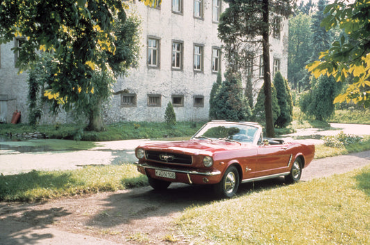 1965 Ford Mustang on scenic road with trees HV 1965-0145