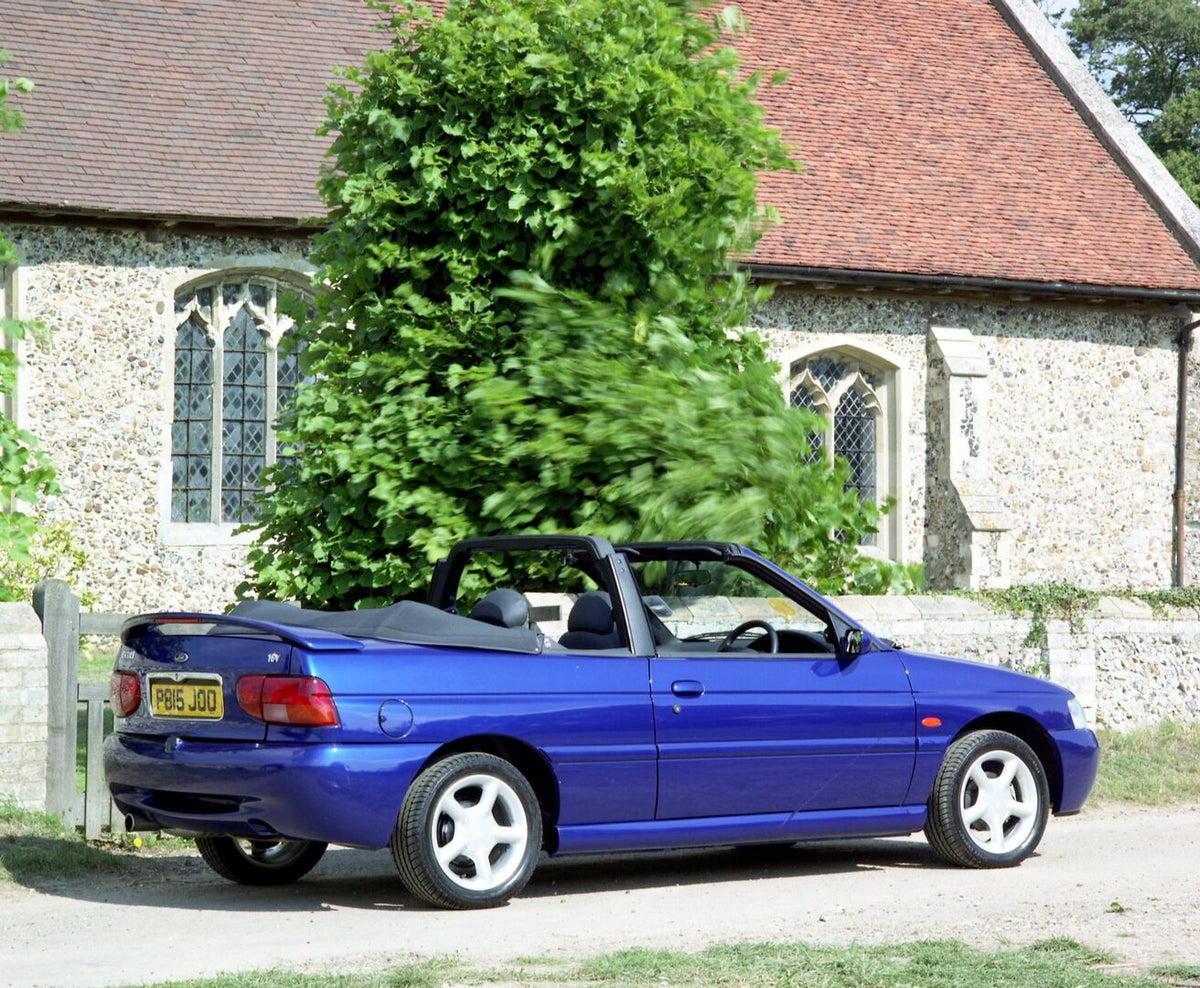 This archival image documents the 1996 Ford Escort Mark VI Cabriolet Ghia rear view in front of scenic building and is preserved in the Ford Heritage Vault as part of Ford Motor Company's historic photographic archive. Free for personal, non-comme...