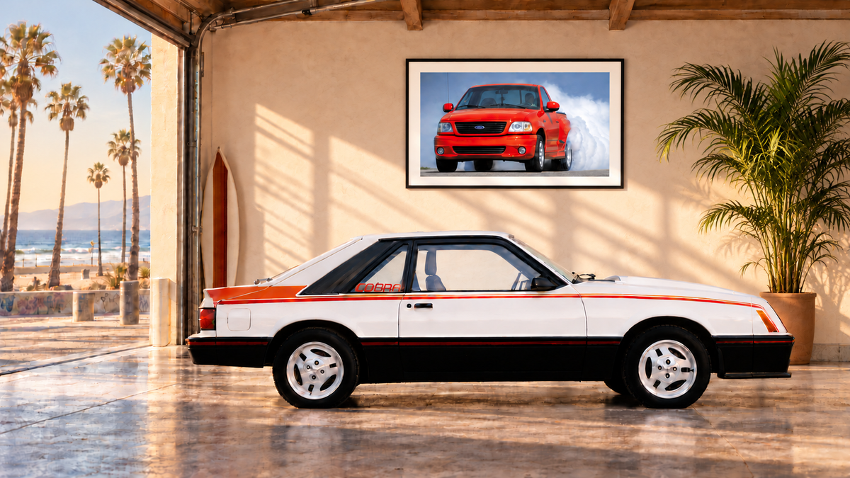 White 1981 Ford Mustang Cobra in a Venice Beach garage with a framed red Ford SVT F-150 Lightning photograph and an indoor palm, overlooking the Pacific Ocean.